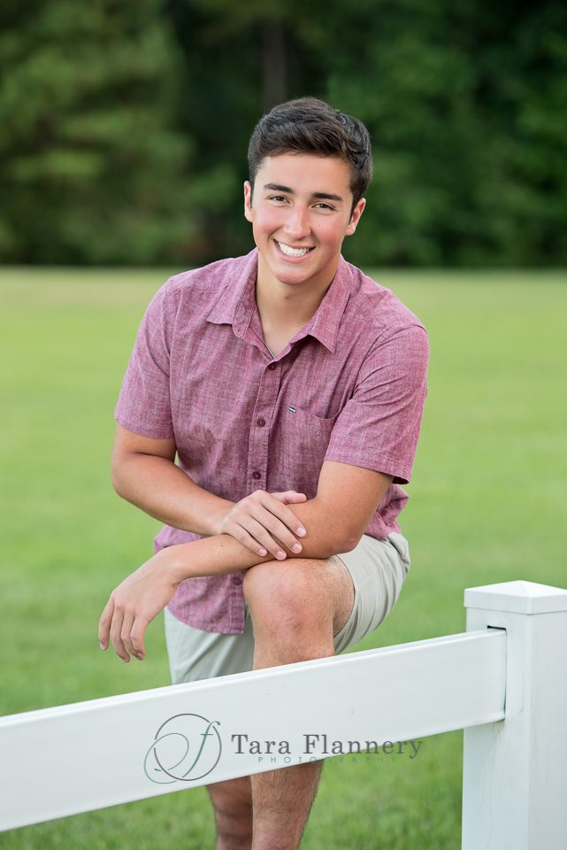 Senior Picture poses boy leaning on white fence
