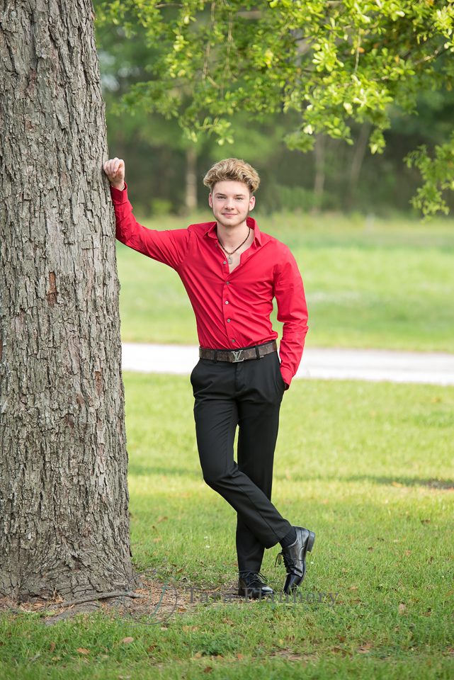 male senior portrait standing by tree