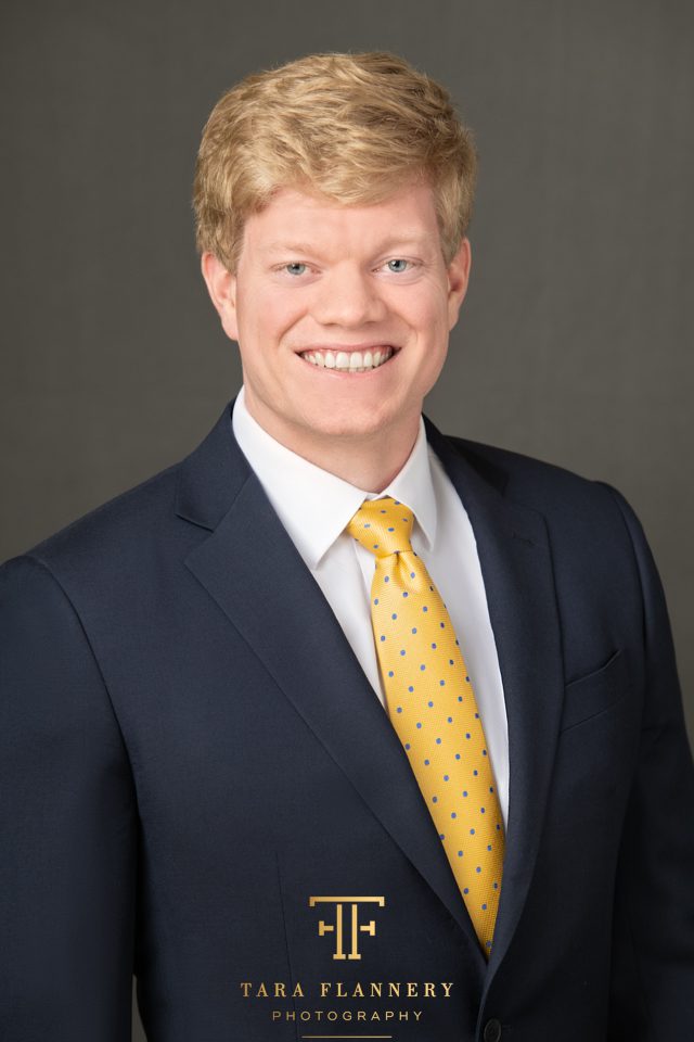 business professional headshot of man in blue suit and yellow tie