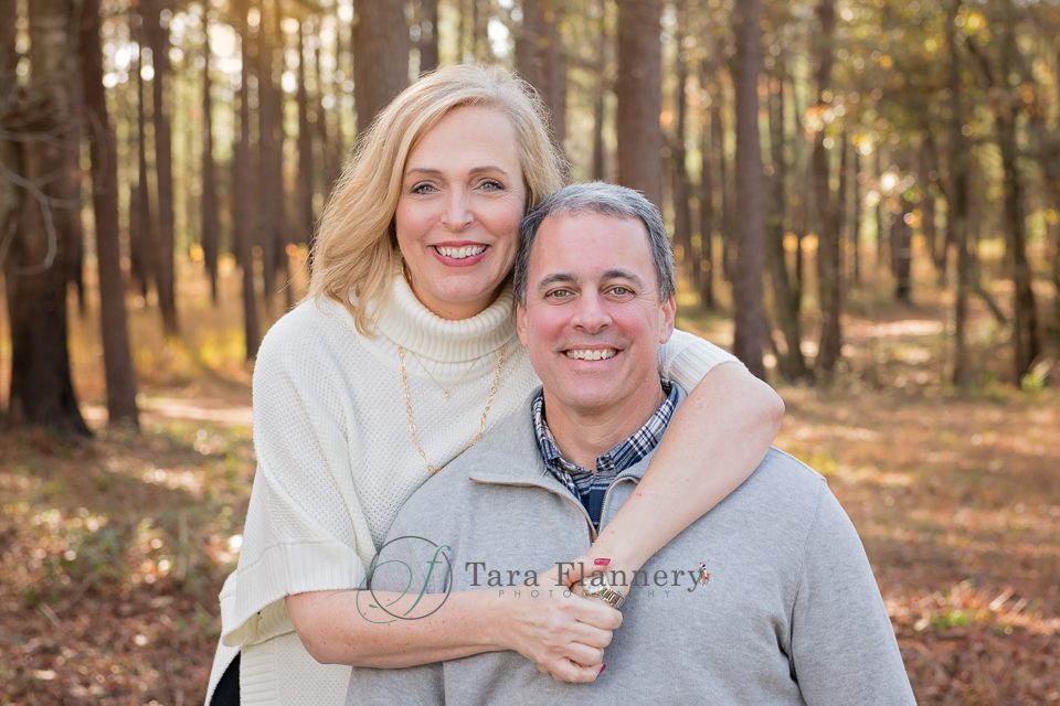 couple posing for family portraits in the woods