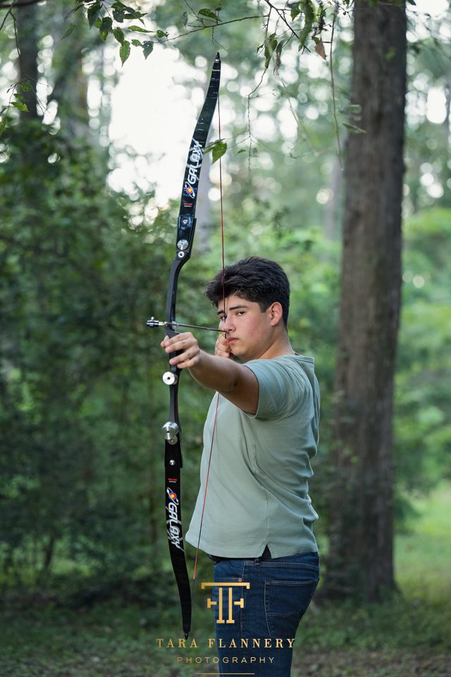 High school senior boy with his bow to celebrate his passion for archery.