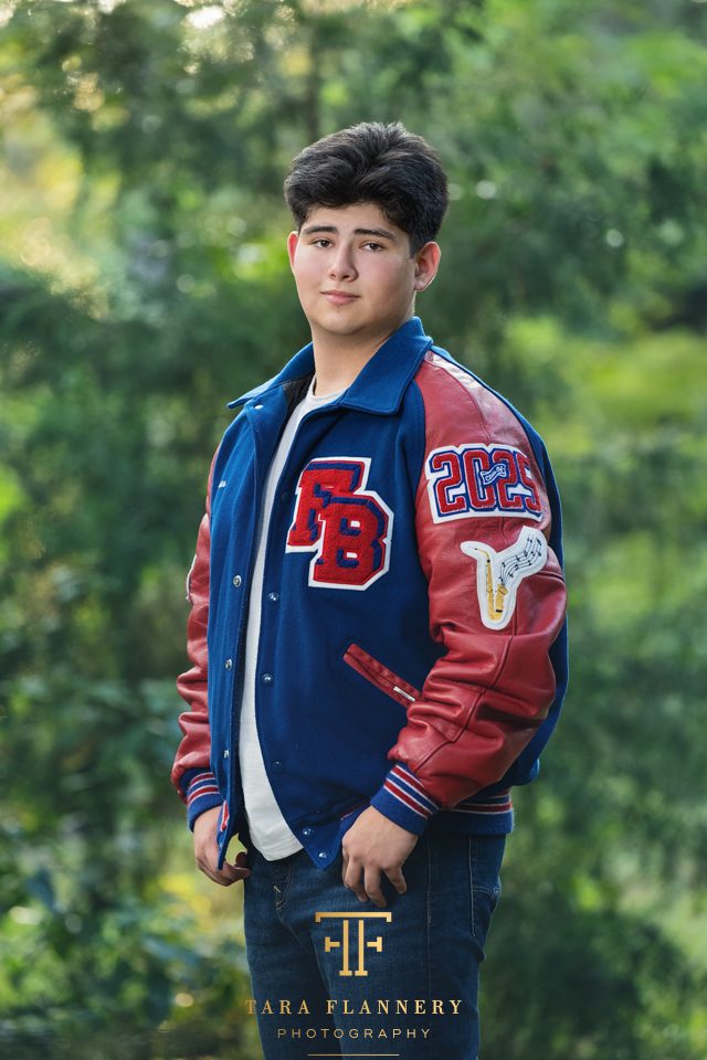 Senior boy with letter jacket poses for a senior picture.