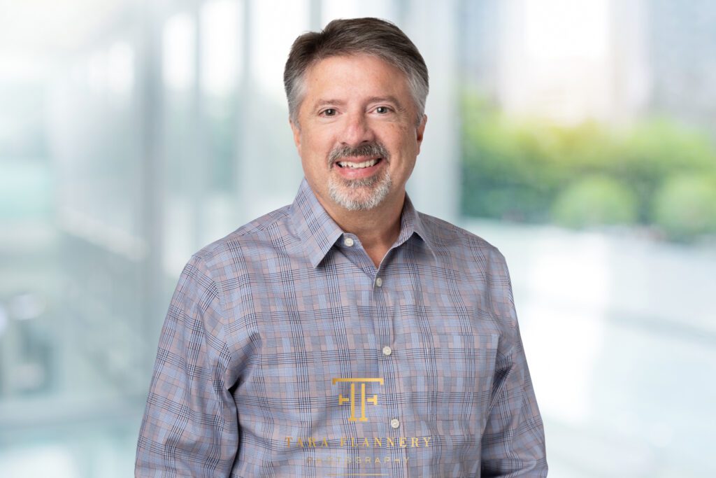 Business man in button-down shirt smiling for a professional headshot.