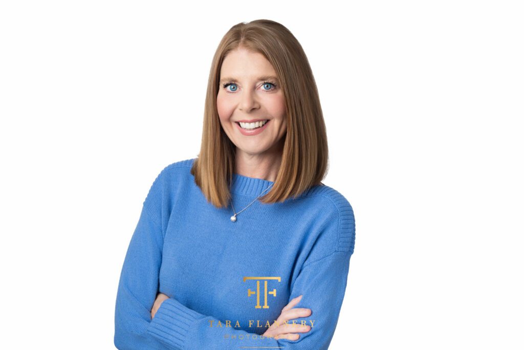 Woman in blue sweater smiles for a professional headshot.