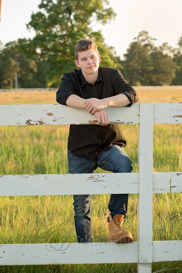 senior boy standing with fence