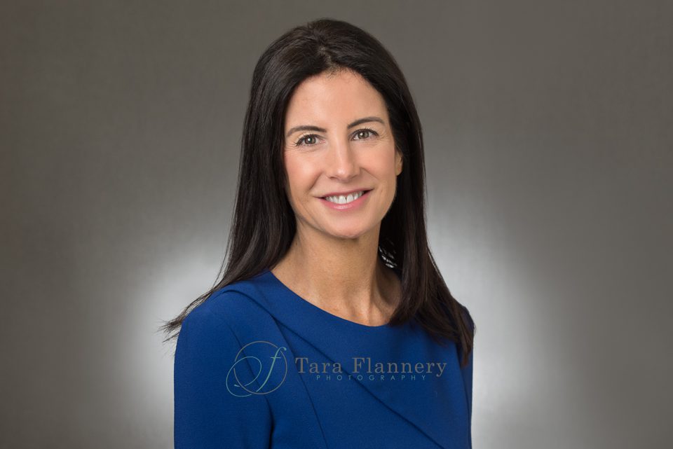 woman in blue dress and grey background headshot