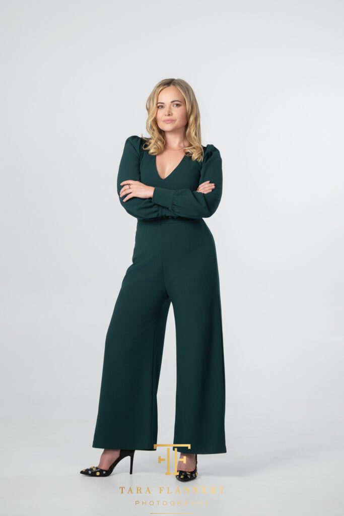 Woman in green pants suit poses for a branding session photo.