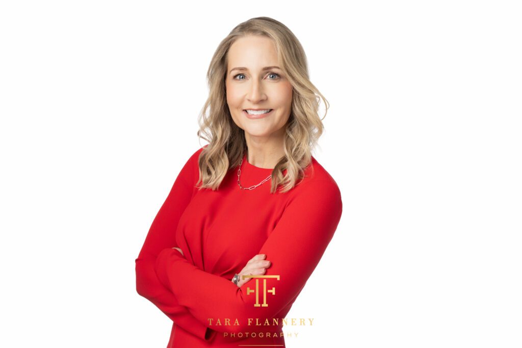 Female executive in red dress poses for a professional corporate headshot.