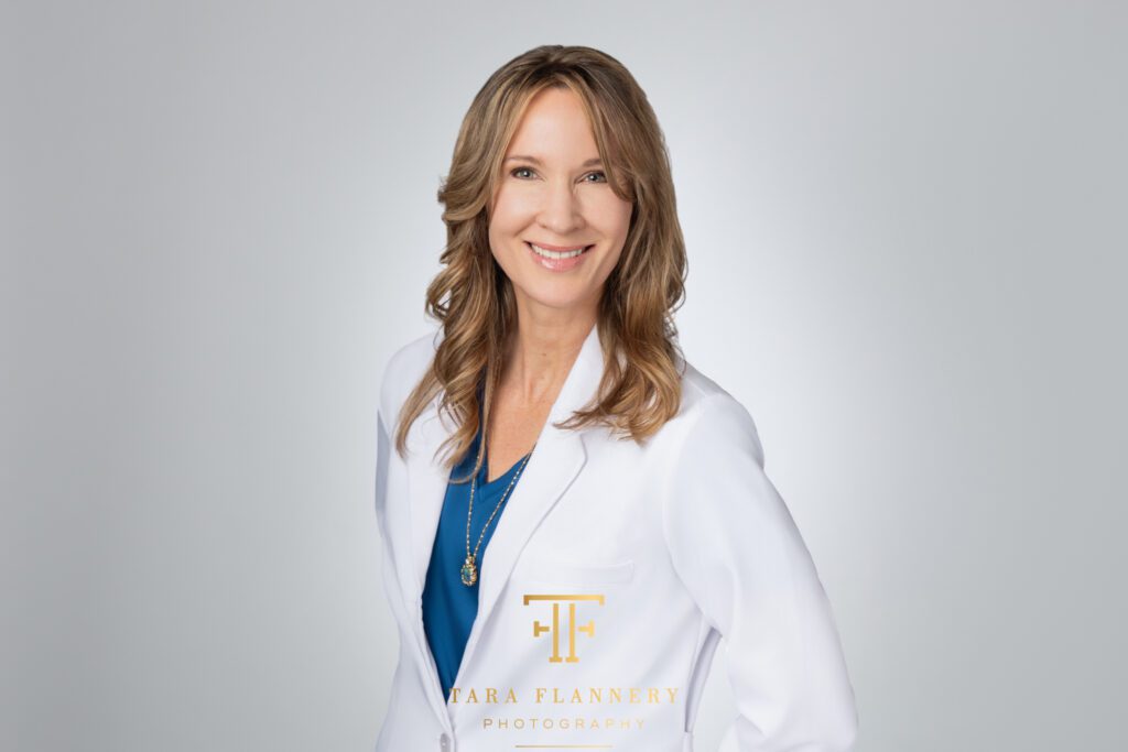 Female medical doctor in white lab coat poses for a professional headshot.