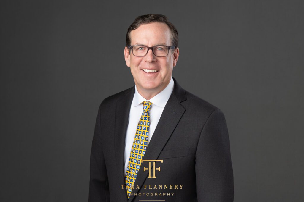 Financial advisor in dark suit and tie poses for a professional headshot.