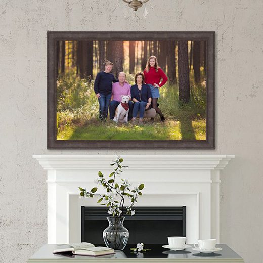 Large custom framed wall art of family portraits over a mantle.