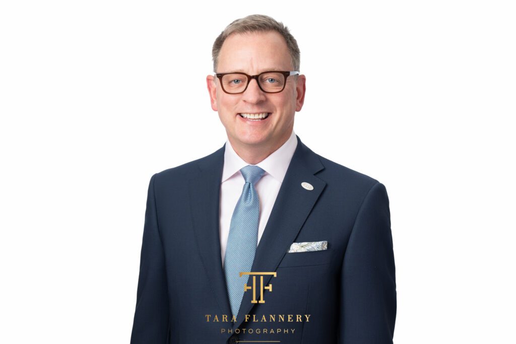 Business professional in suit and tie smiling for a corporate headshot.