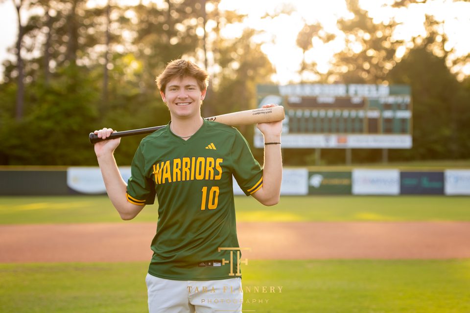 High school baseball player poses on the field for his senior photography session in The Woodlands Texas.